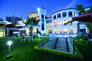 A modern hotel with a central atrium, outdoor seating, and a glass staircase.
