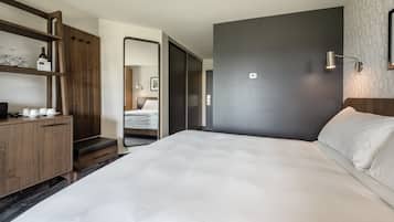 Ein modernes Hotelzimmer mit einem großen Bett, Holzmöbeln, einem Spiegel und einer Wandleuchte.