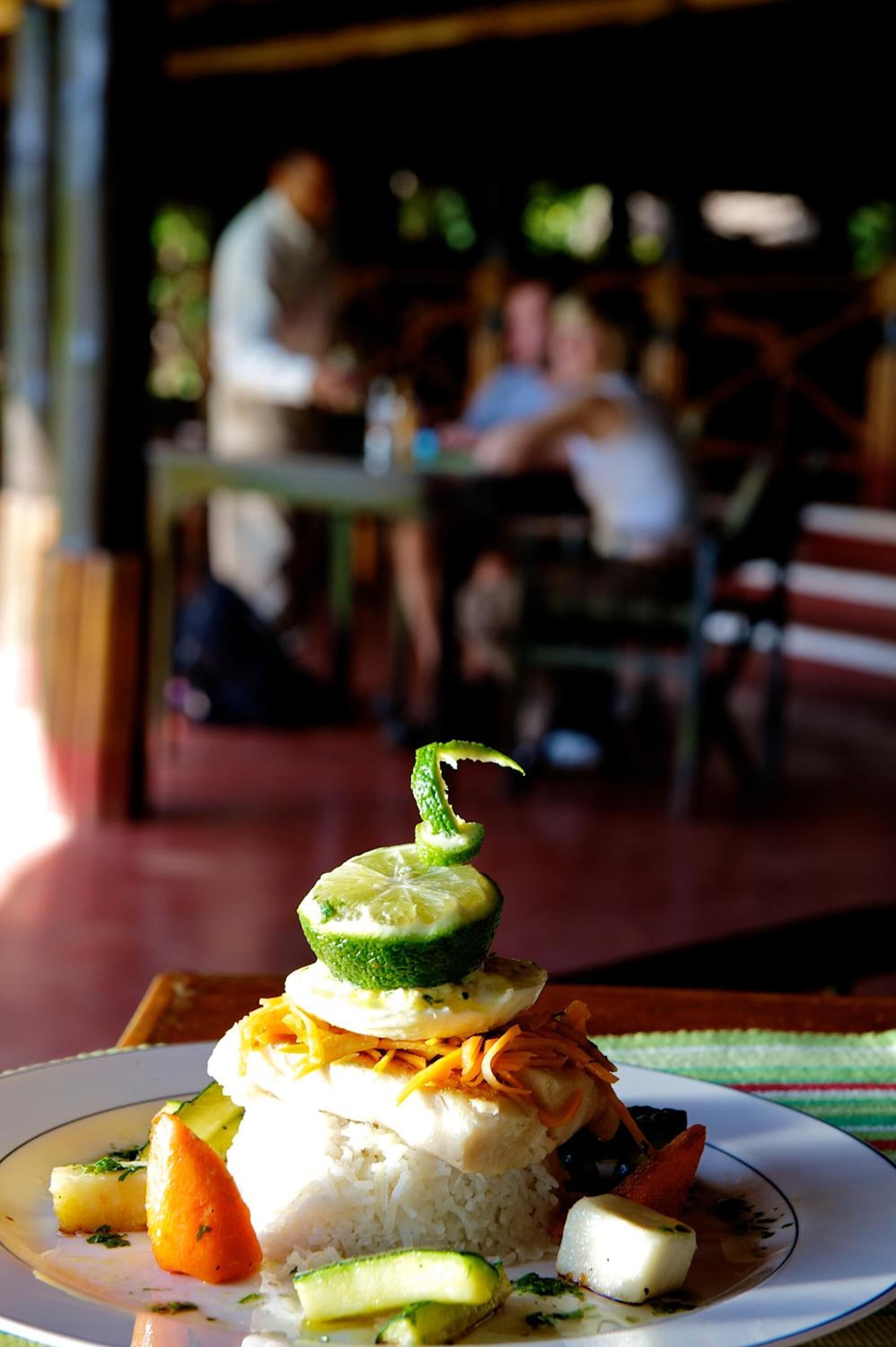 A plate of food with rice, vegetables, and a lime garnish.
