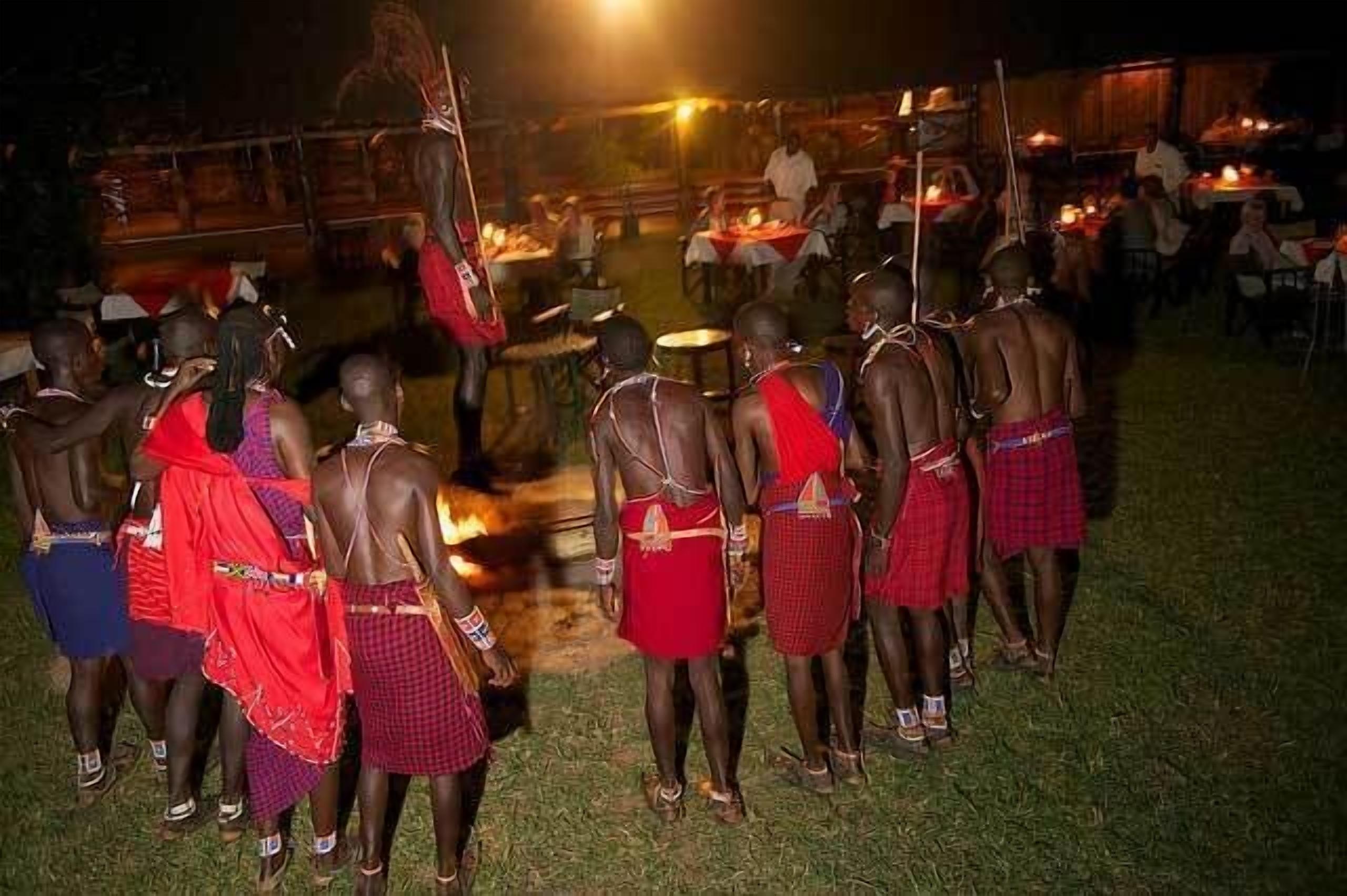 A group of people in traditional attire gathered around a fire, possibly for a cultural event.
