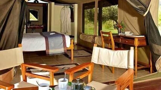 Ein Zelt mit einem Bett, einem Esstisch mit Stühlen und einer kleinen Küchenzeile.