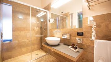 A modern bathroom with a glass-enclosed shower, a large sink, and a towel rack.