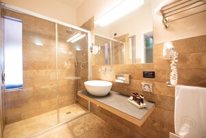A modern bathroom with a glass-enclosed shower, a large sink, and a towel rack.