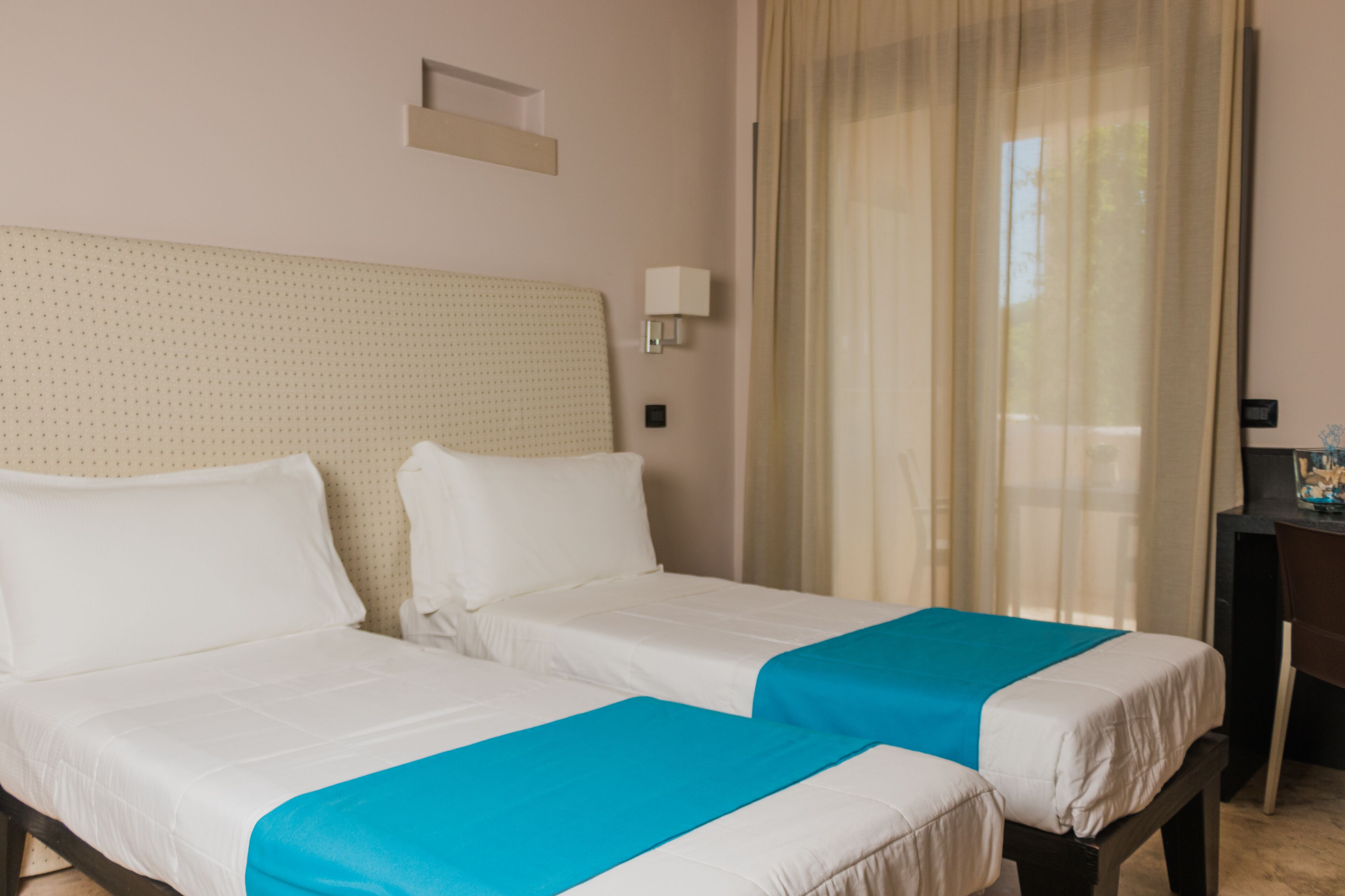 Una habitación de hotel con dos camas, un escritorio y una ventana con cortinas.