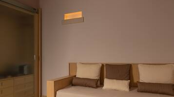 Un dormitorio con cama, almohadas, una mesita de noche y un aplique de pared.