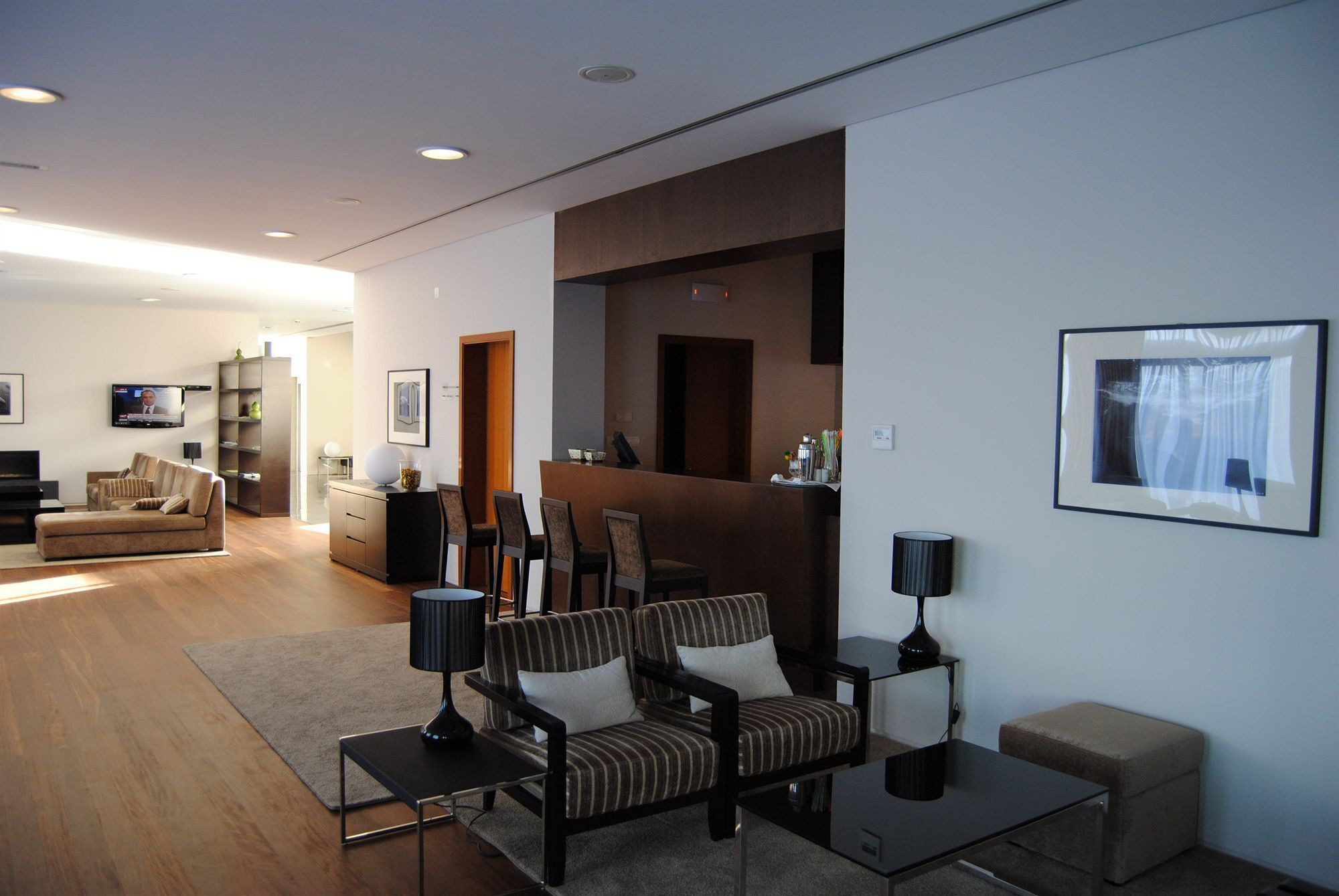 Un salon moderne avec un canapé, des fauteuils, une table basse, un téléviseur et un tableau encadré accroché au mur.