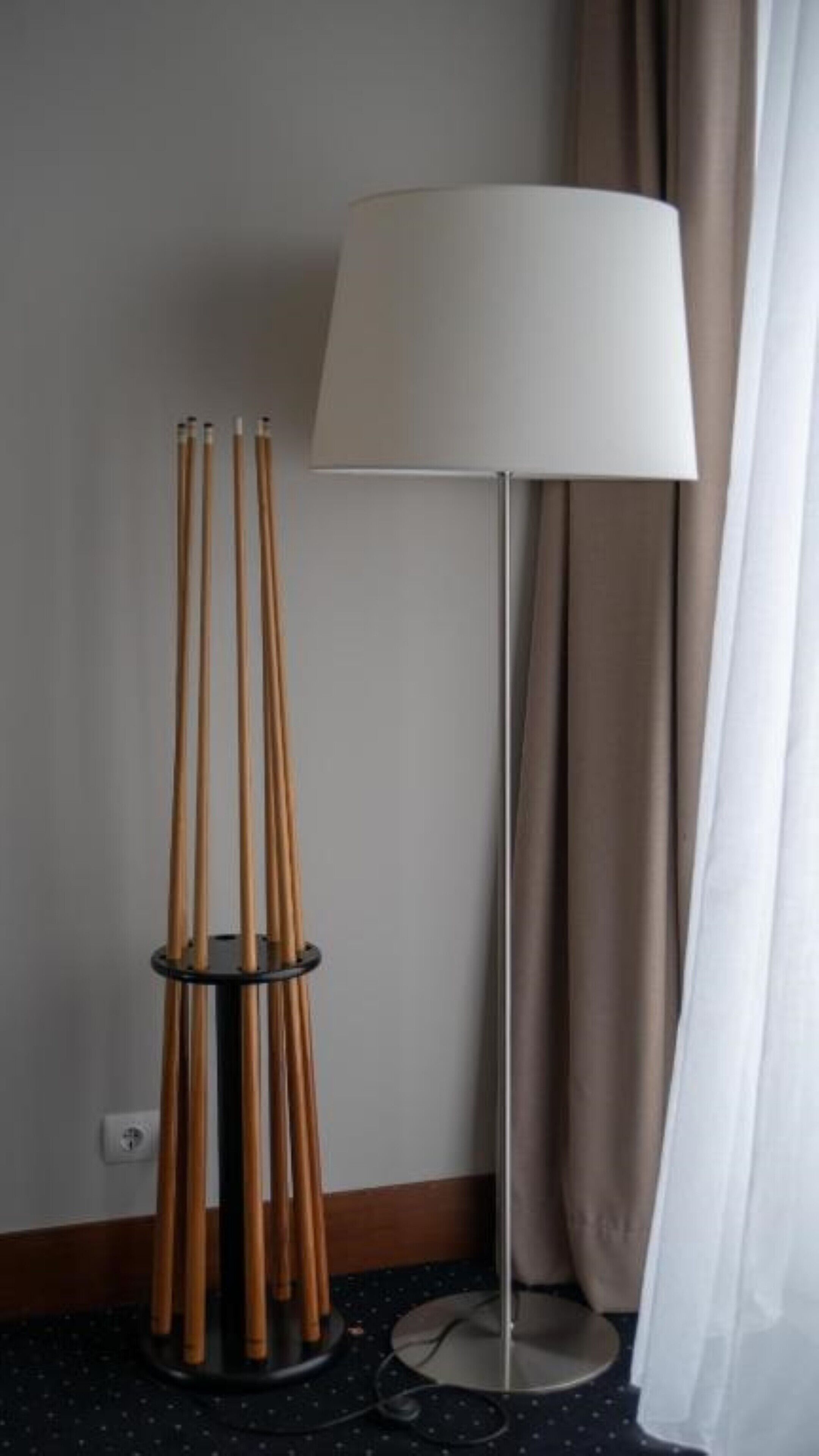 Une pièce avec un lampadaire et un support contenant plusieurs bâtonnets de bois.