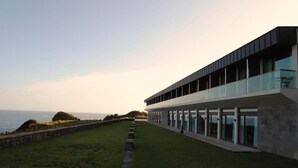 A modern building with a long, straight pathway leading to a glass balcony overlooking the sea. - Inatel Flores Hotel (Santa Cruz das Flores)