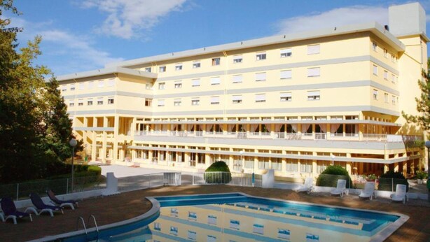 Un hôtel à plusieurs étages doté d’un espace piscine comprenant des chaises longues et une piscine.