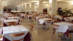 Une grande salle à manger avec de nombreuses tables et chaises, disposées en rangées.