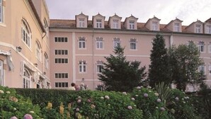 A building with a row of windows and a garden with various plants and flowers. - INATEL Luso (Mealhada)