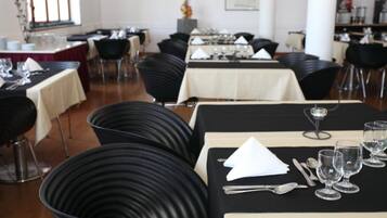 Comedor con varias mesas dispuestas para el servicio, sillas negras y una paleta de colores neutros.