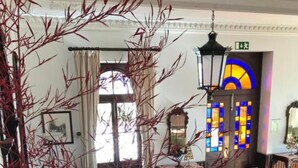 A grand staircase with a checkered floor, leading to a room with a large window and a stained glass door. - INATEL Luso (Mealhada)