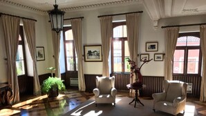 A spacious room with a checkered floor, two armchairs, a small table, and a potted plant. - INATEL Luso (Mealhada)