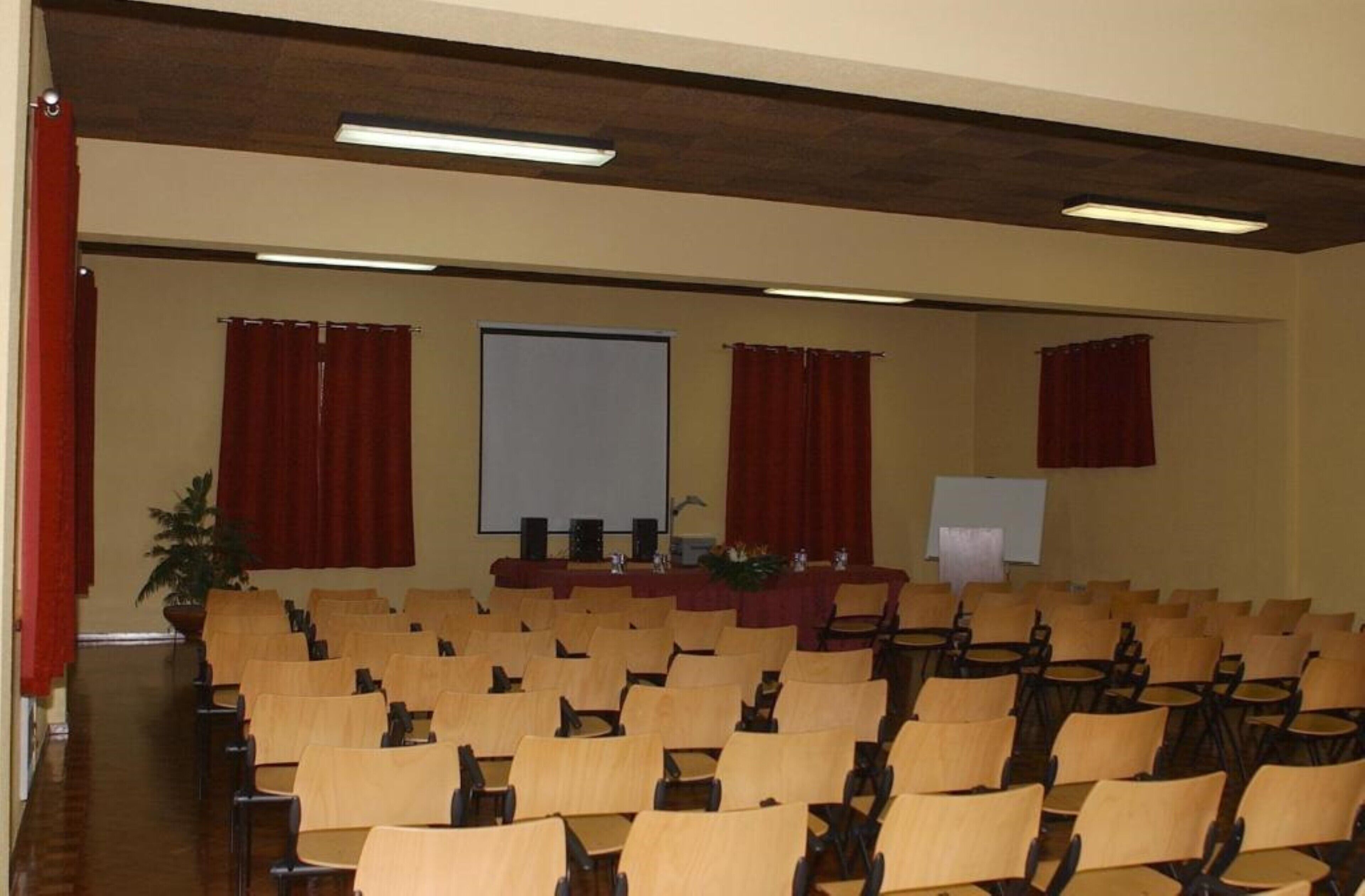 A conference room with rows of chairs, a projector screen, and a podium.