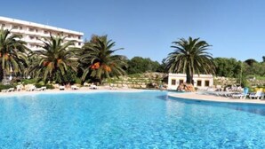 Una amplia piscina al aire libre rodeada de palmeras y un edificio de hotel.