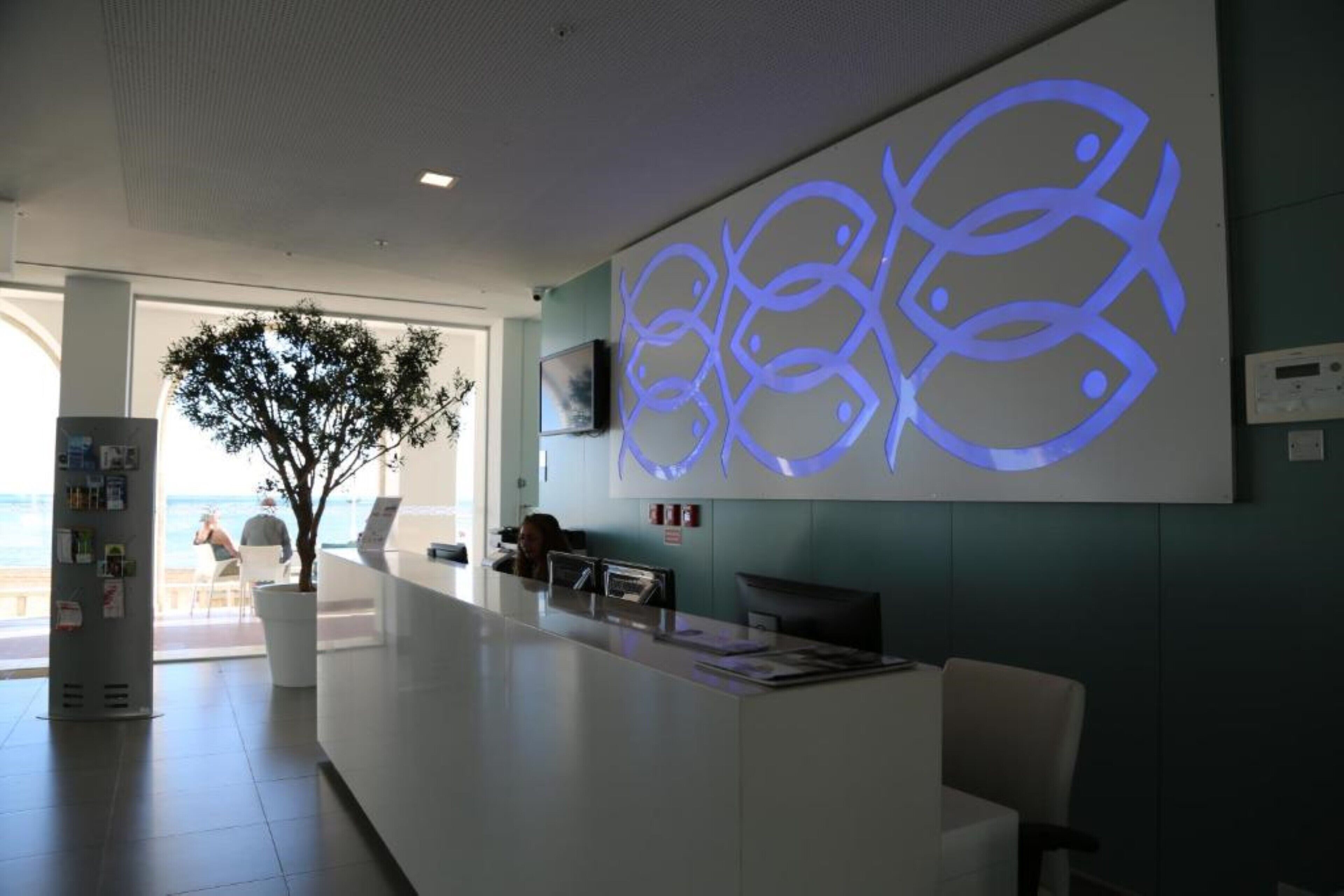 A reception area with a modern design, including a reception desk, seating area, and a large wall art piece.