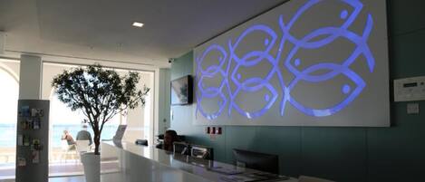 A reception area with a modern design, including a reception desk, seating area, and a large wall art piece.
