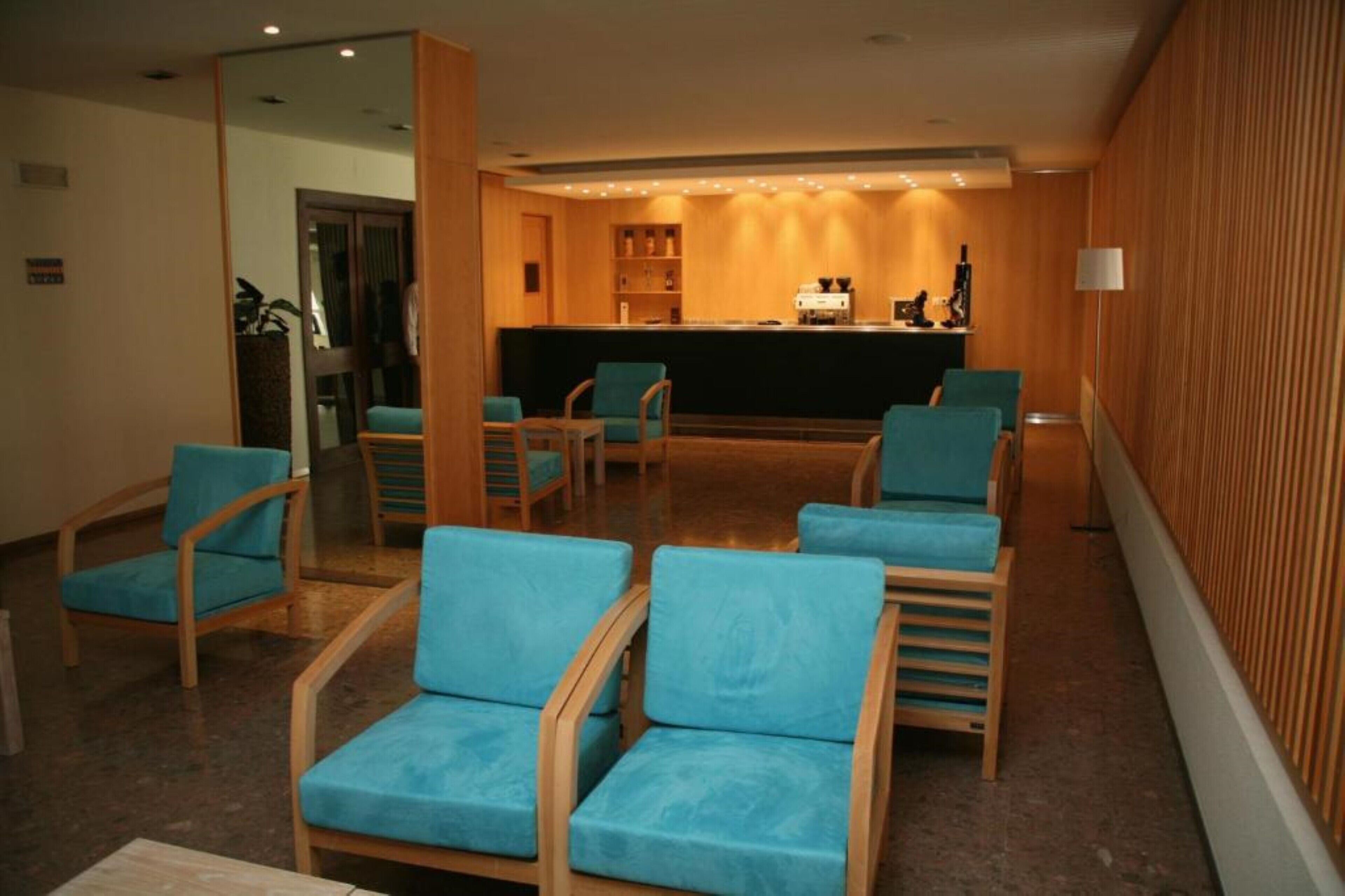 A lobby with wooden walls, a reception desk, and several blue chairs.