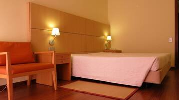 Una habitación de hotel con cama, escritorio, silla y dos lámparas de noche.