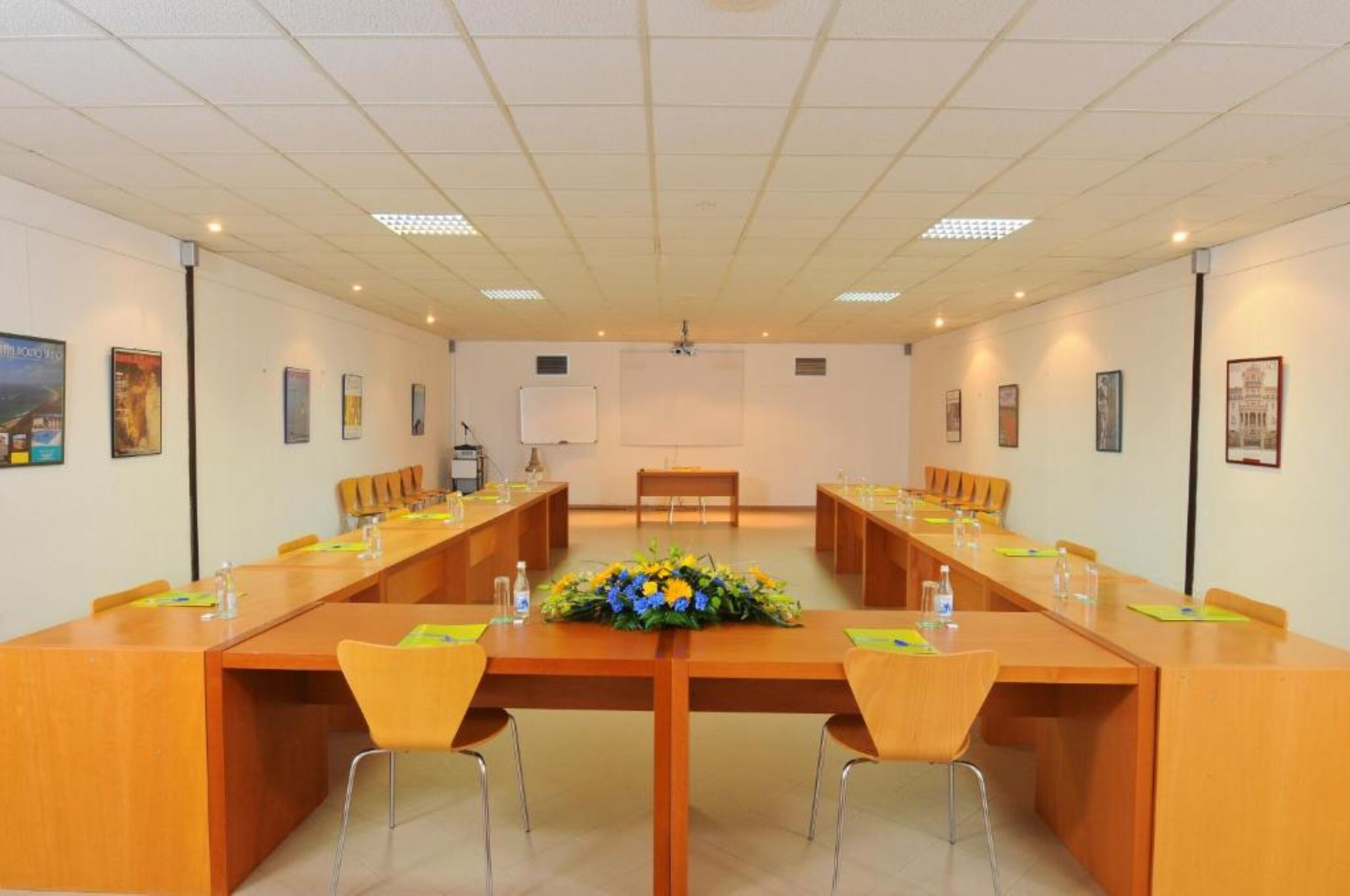 A conference room with a long table, chairs, a whiteboard, and framed pictures on the walls.