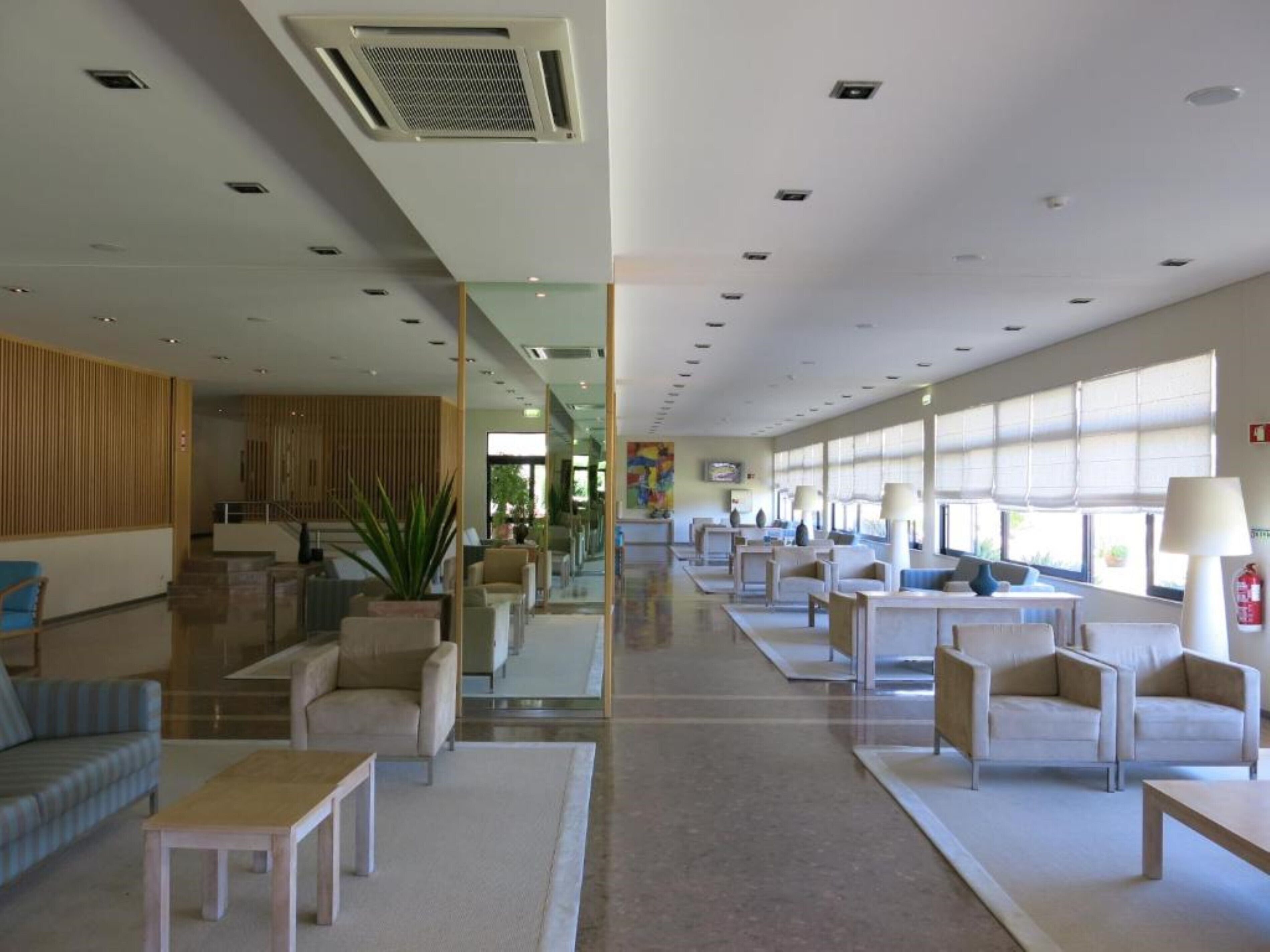 A spacious lobby with a central staircase, comfortable seating areas, and large windows providing natural light.