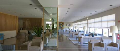 A spacious lobby with a central staircase, comfortable seating areas, and large windows providing natural light.