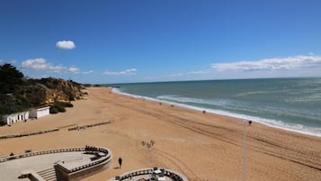 Una playa con una zona de estar circular y un edificio con escaleras que bajan a la arena.