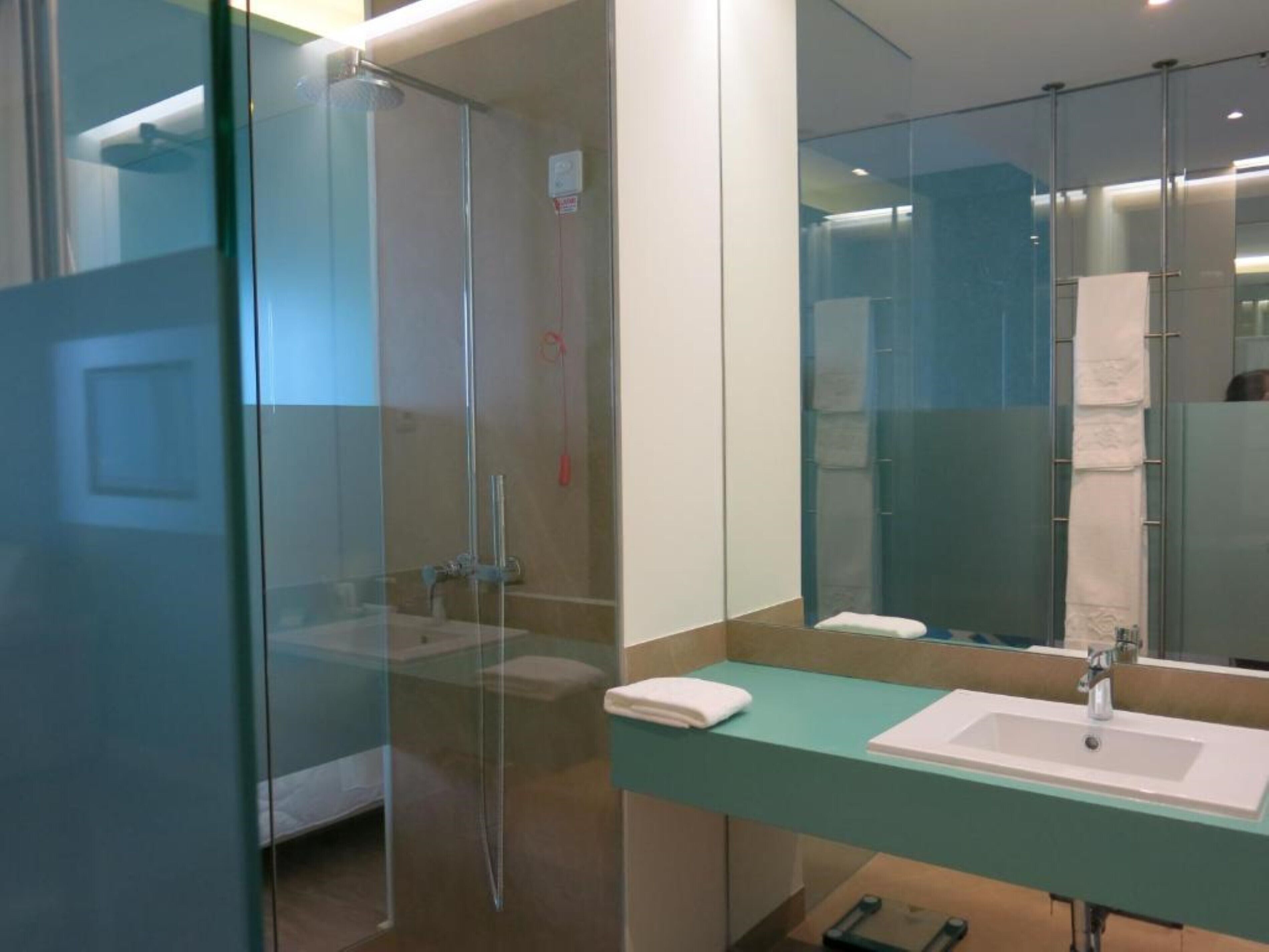 Ein modernes Badezimmer mit einer Duschkabine, einem Waschbecken und einem Spiegel.