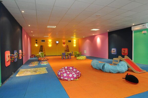 A brightly colored play area with a slide, bean bags, and a mat with a map.