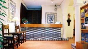 A reception area with a tiled wall, wooden reception desk, chairs, and a statue. - INATEL Castelo de Vide (Castelo de Vide)