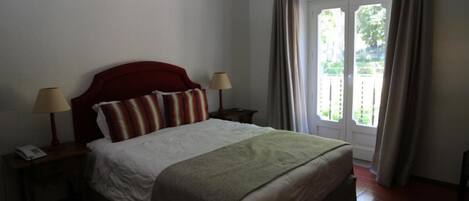 A bedroom with a bed, two bedside tables, a lamp, and a window with curtains.