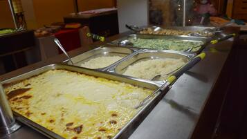 A buffet with various food options including a casserole dish, rice, and a green vegetable dish.