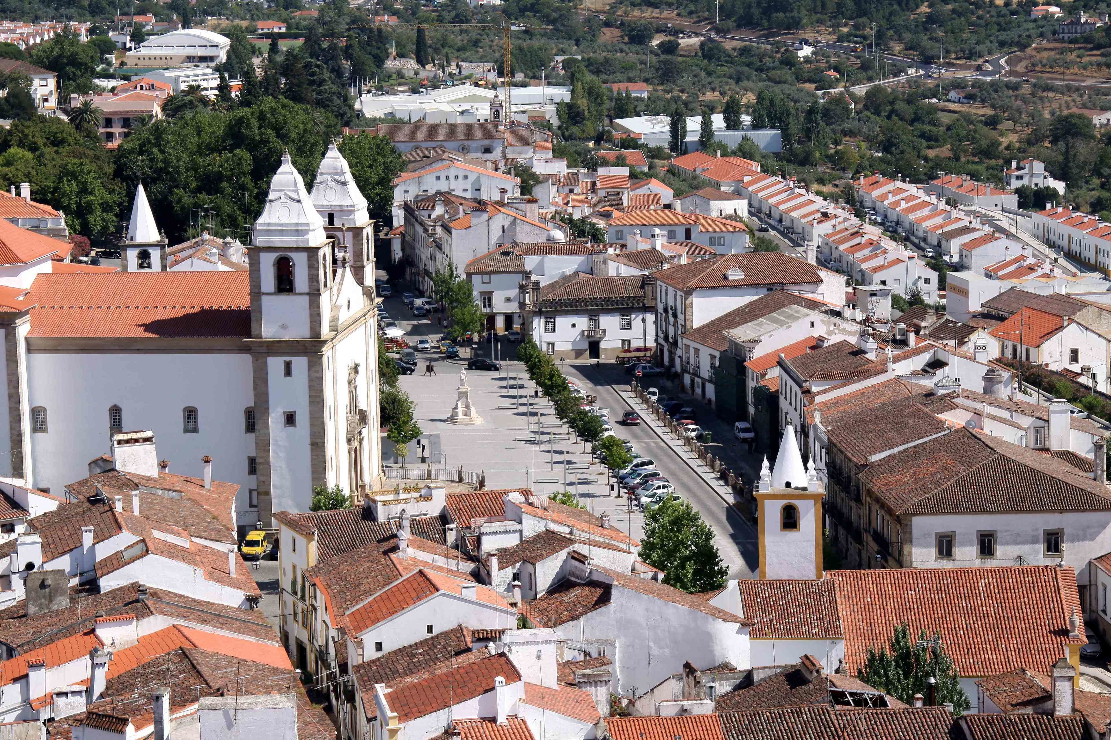 A densely packed urban area with white buildings and red-tiled roofs, featuring a prominent white church with a bell tower.