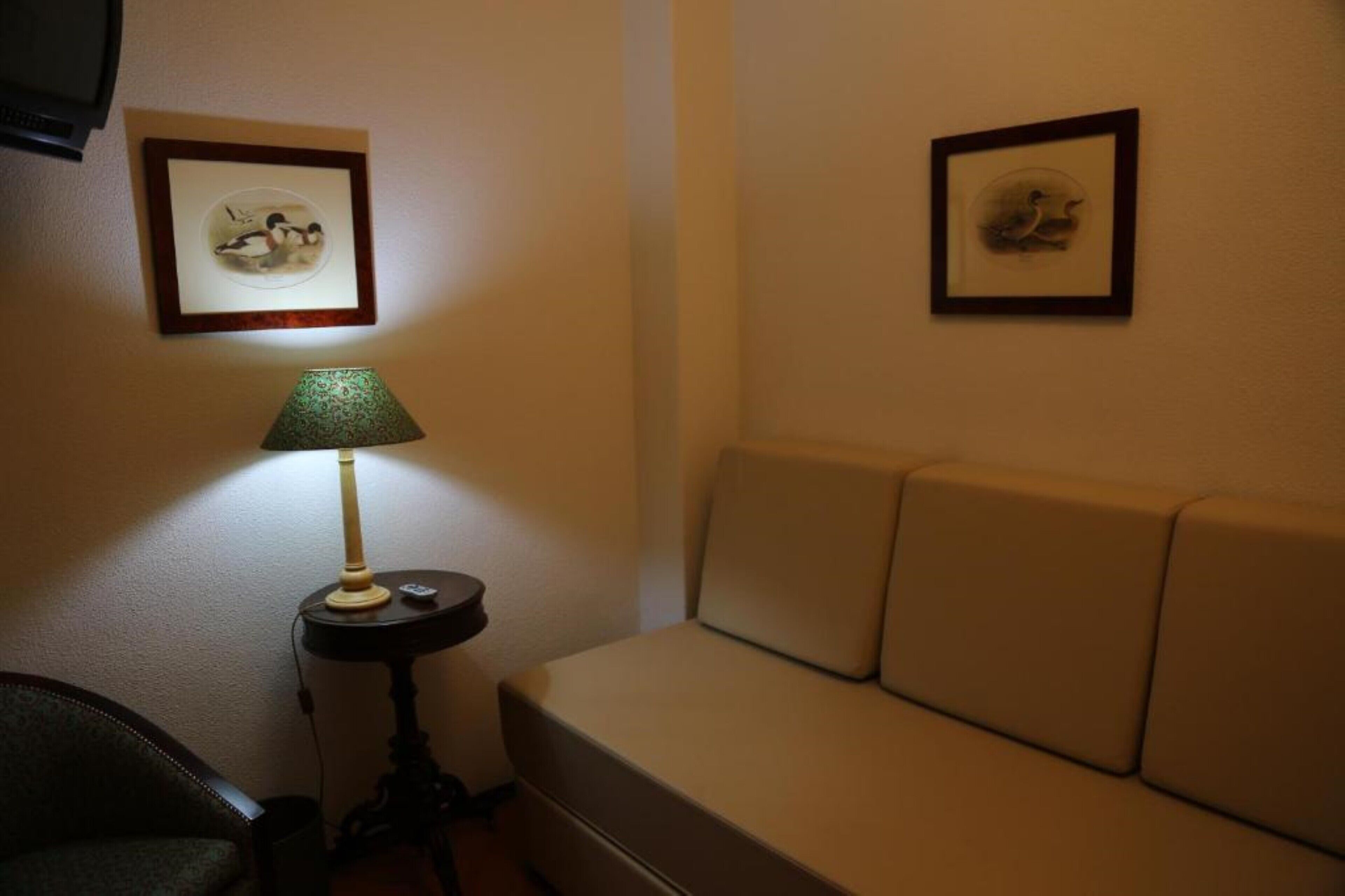 Una habitación con un sofá, una lámpara y dos cuadros en la pared.
