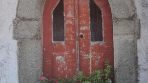 A table set for dining with a red door and potted plants in the background. - INATEL Castelo de Vide (Castelo de Vide)