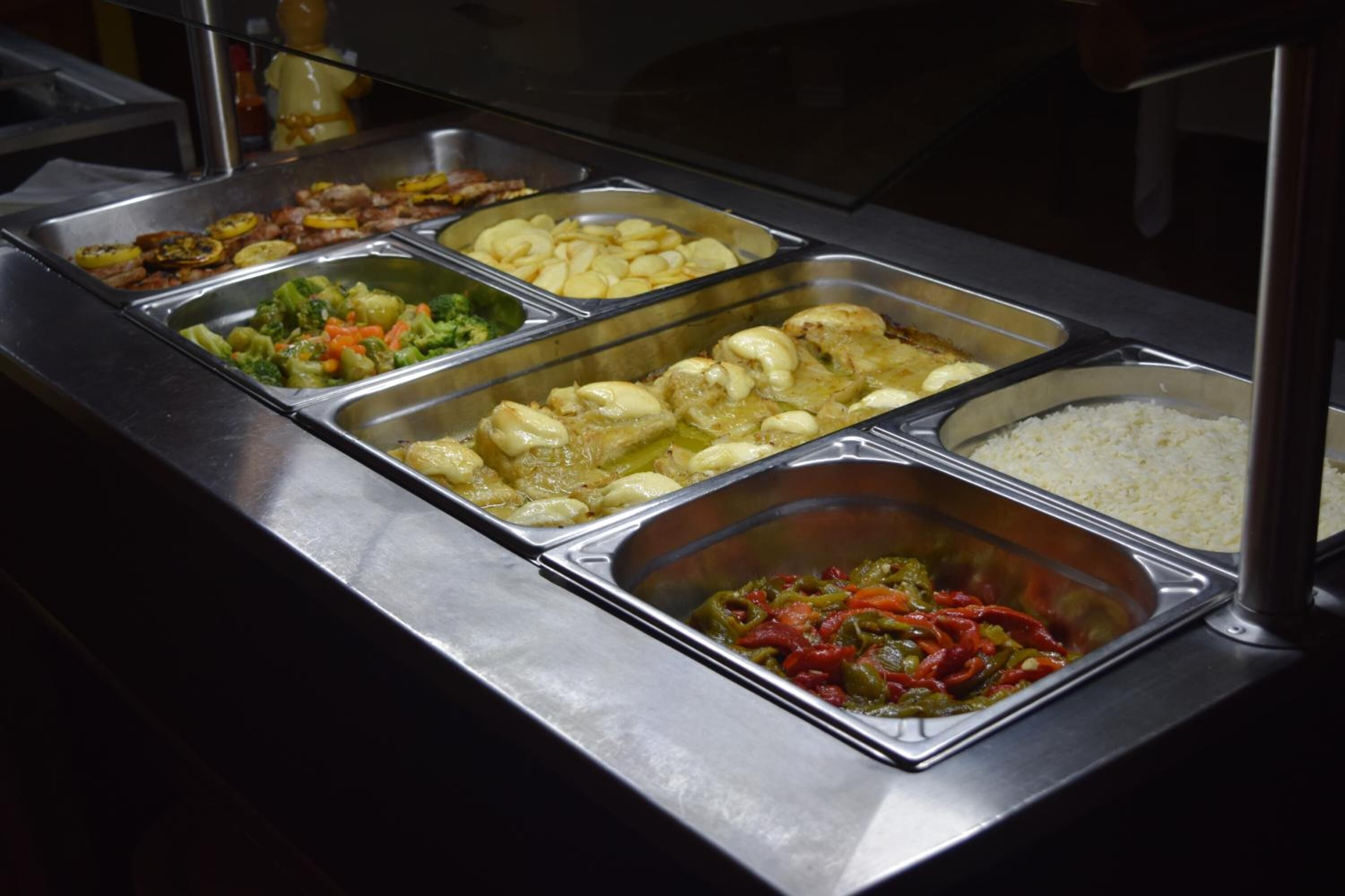 A buffet with various food options including vegetables, rice, and a meat dish.