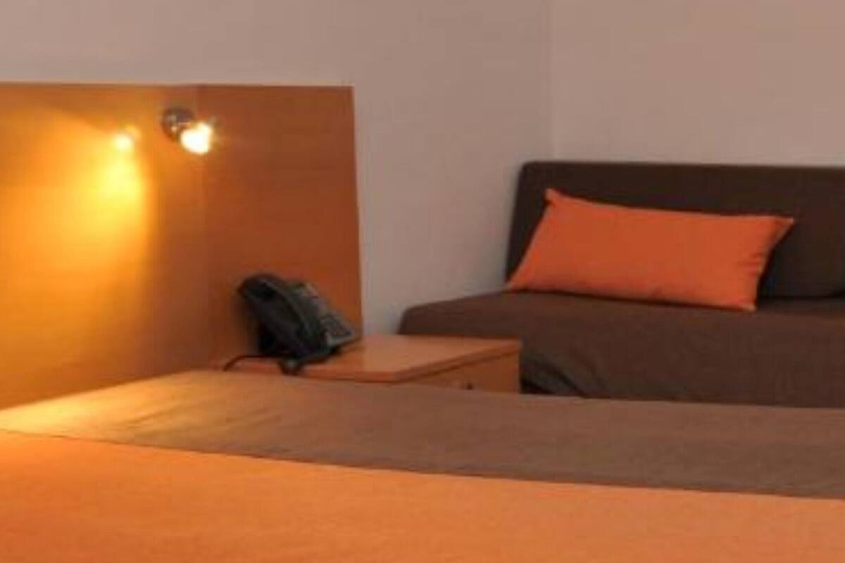 Ein Zimmer mit einem Bett, einem Nachttisch und einer Wandleuchte.