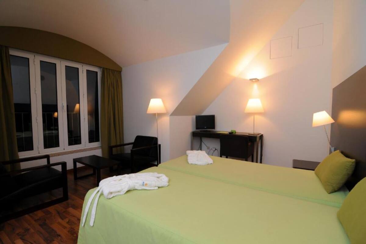 Ein Hotelzimmer mit Bett, Schreibtisch, Stuhl und Fernseher.