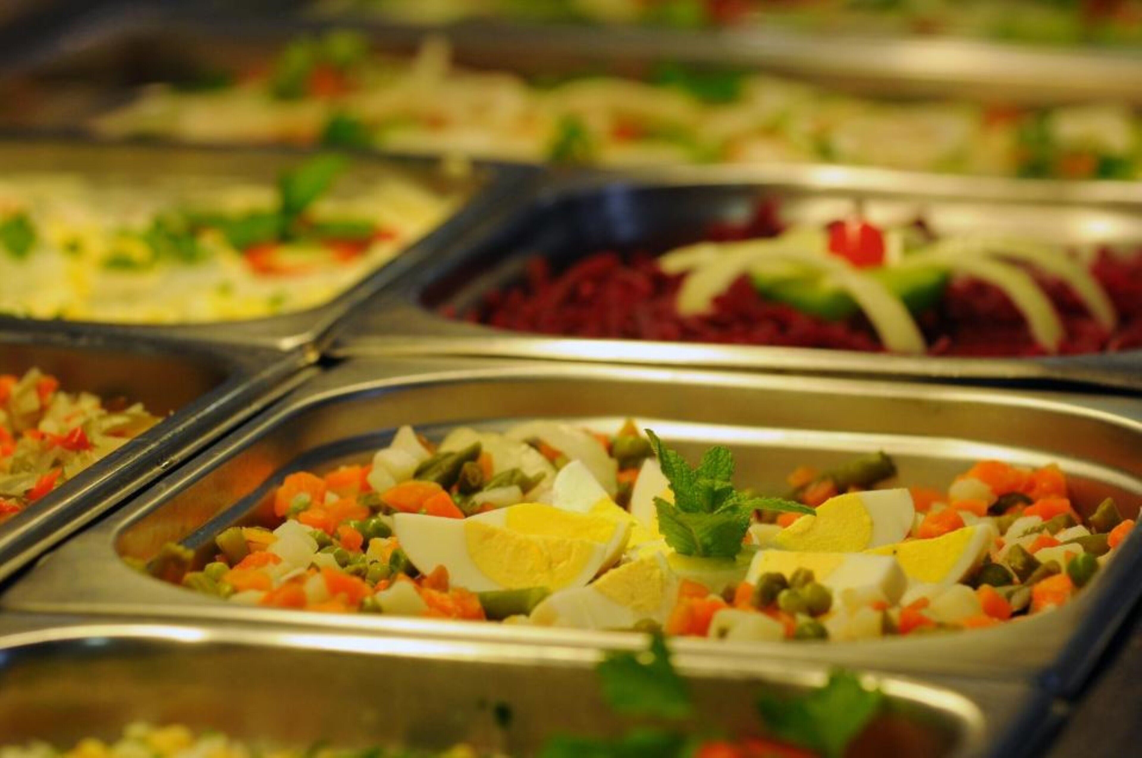 A buffet with various dishes including salads, vegetables, and eggs.