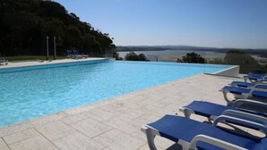 A swimming pool with lounge chairs, a clear view of the landscape, and a tiled deck. - INATEL Foz do Arelho (Caldas da Rainha)