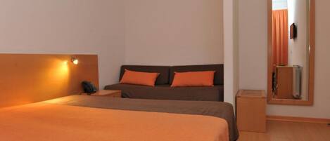 Habitación de hotel con cama, mesita de noche, espejo y una lámpara de pared.