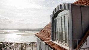 A modern building with a curved facade, large windows, and a view of a beach and water body. - INATEL Foz do Arelho (Caldas da Rainha)