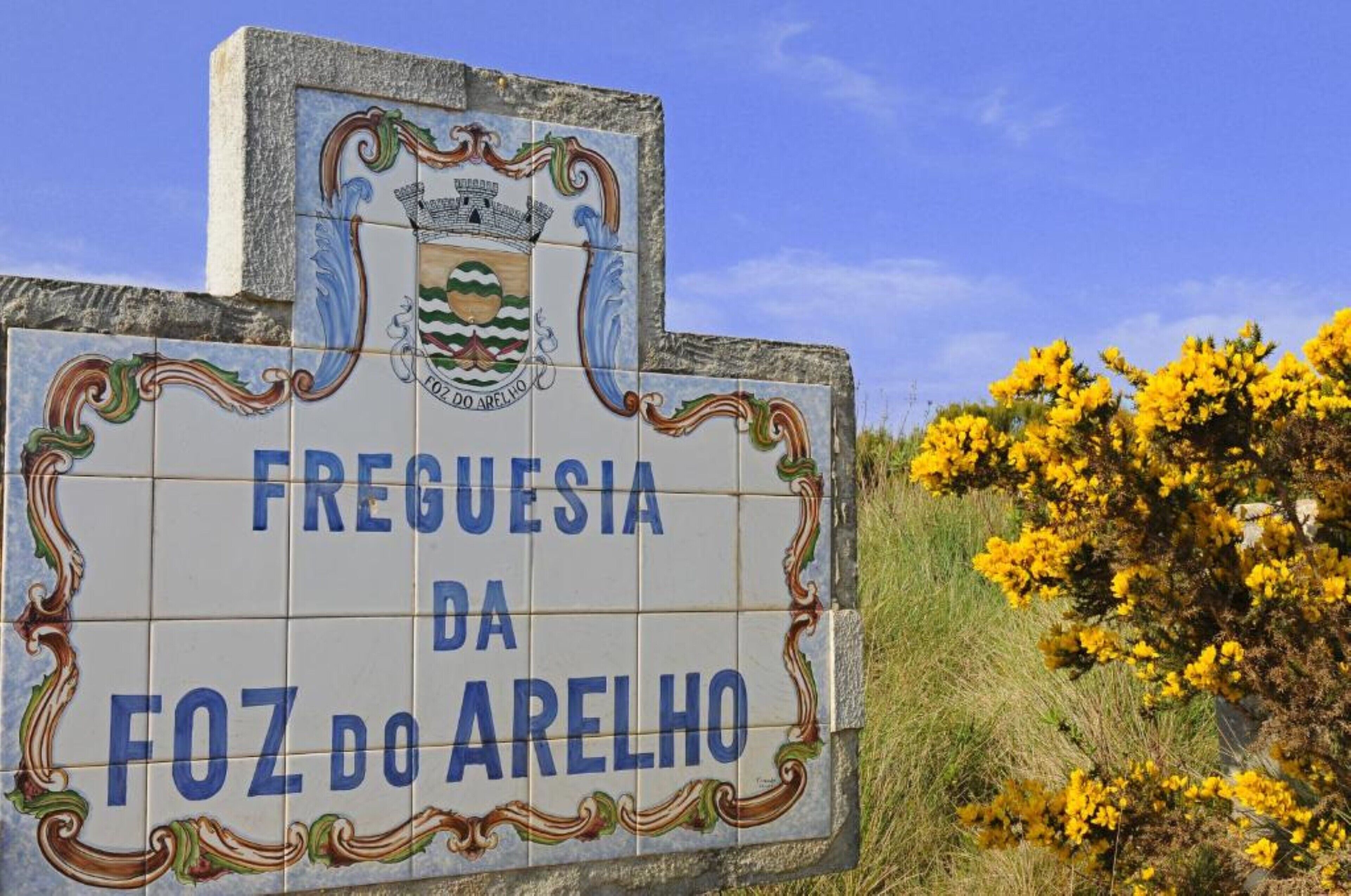 Ein Schild mit dem Text 'FREGUESIA DA FOZ DO ARELHOS' und einem Wappen.