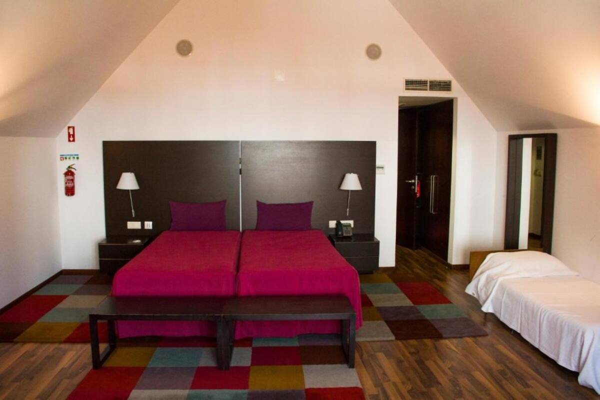 Ein Schlafzimmer mit einem großen Bett, zwei Nachttischen, einer Bank und einem kleinen Tisch.