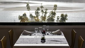 A dining table set for two with a view of a body of water and distant hills. - INATEL Foz do Arelho (Caldas da Rainha)