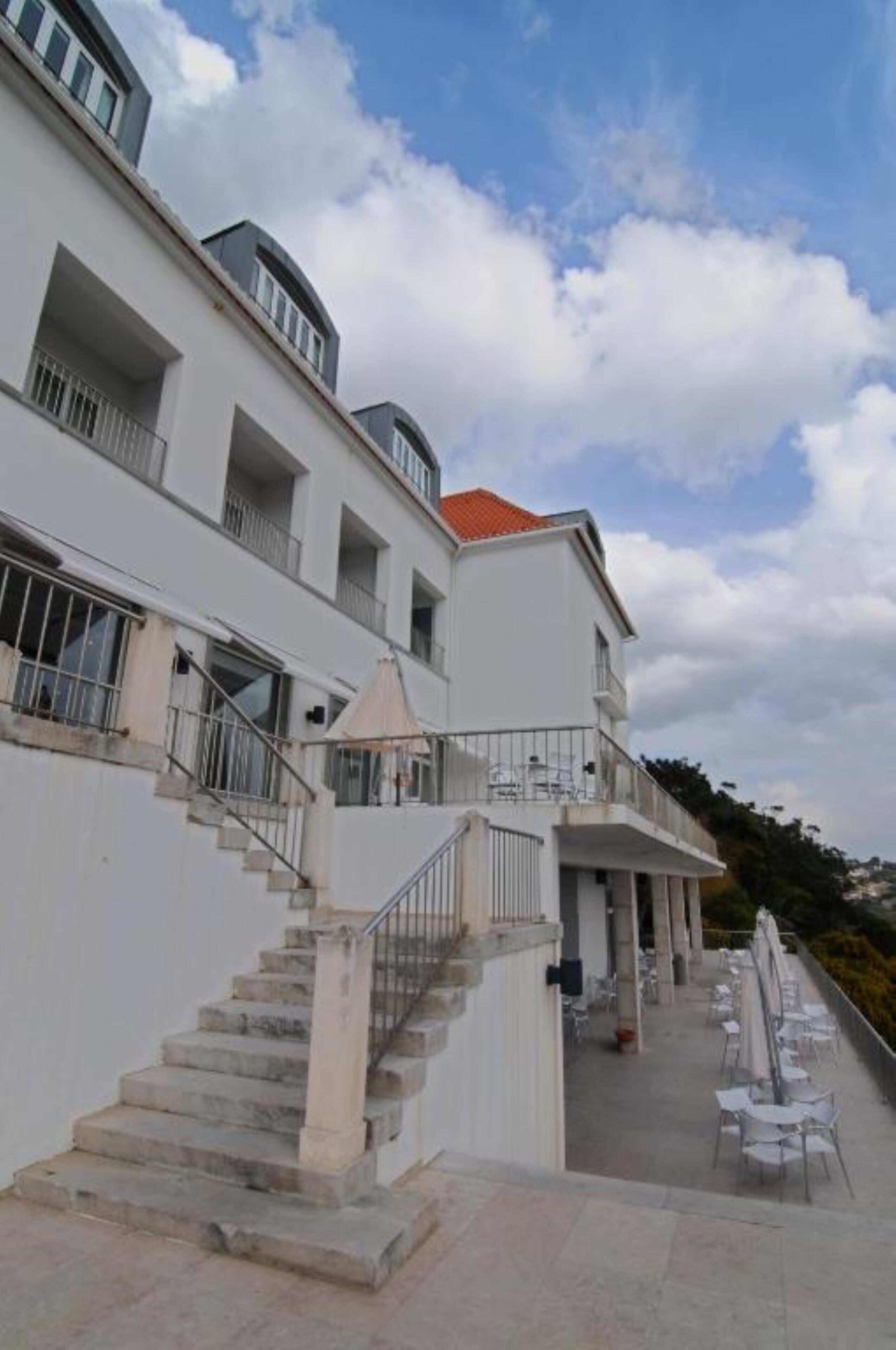 Un immeuble à plusieurs étages, doté d’un escalier menant à un balcon agrémenté d’un espace aménagé pour s’asseoir à l’extérieur.