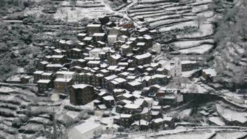 Un village enneigé, avec des maisons à étages et une église imposante.