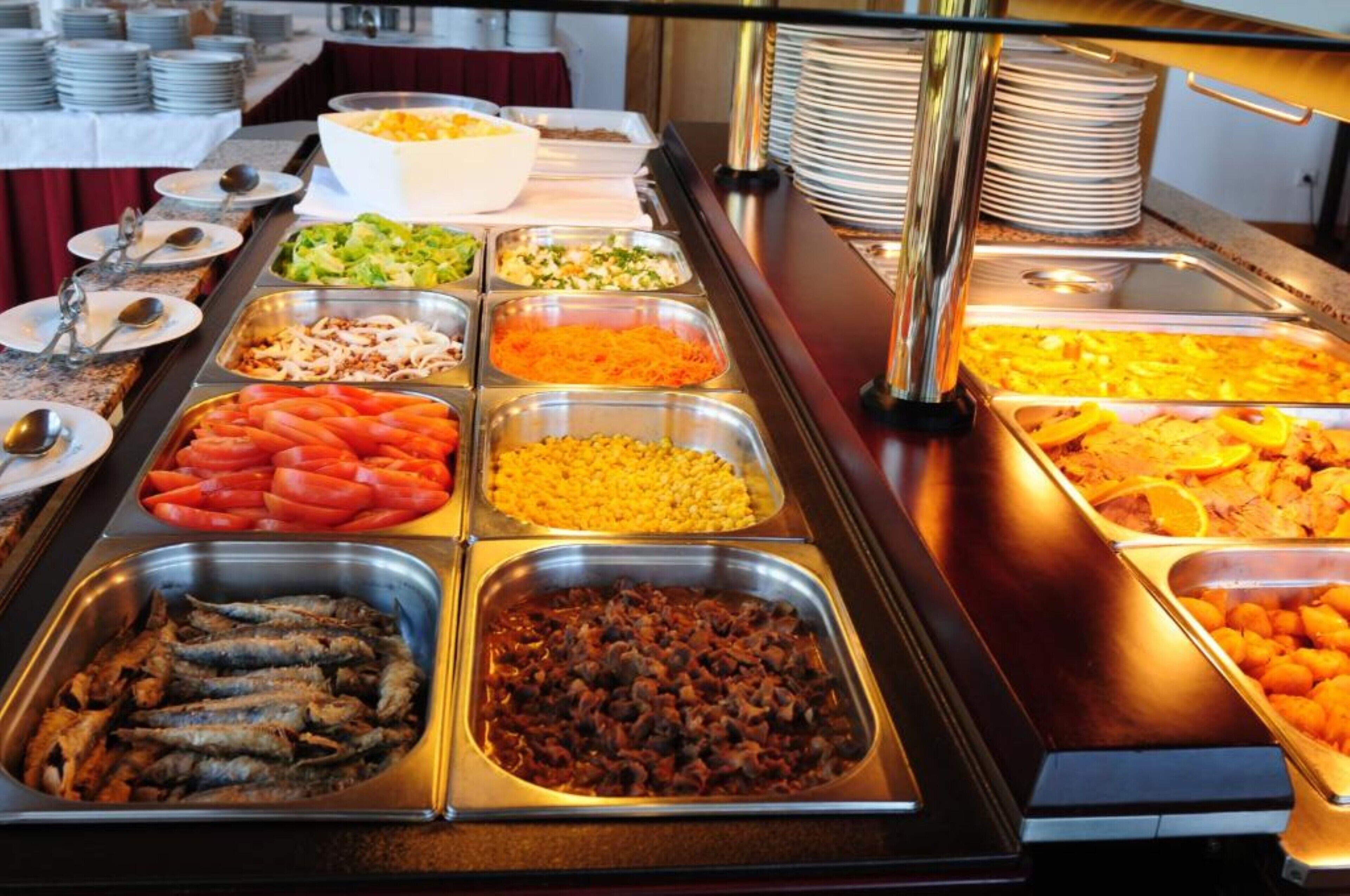 Un buffet proposant une variété de plats, notamment des légumes, de la viande et des fruits de mer.