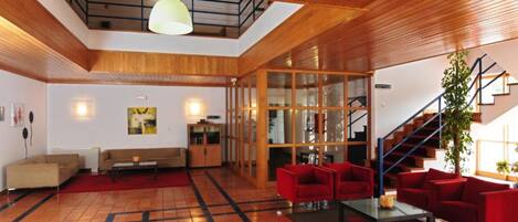 Un vaste espace de vie doté d’un plafond en bois, d’un escalier et d’un canapé rouge.